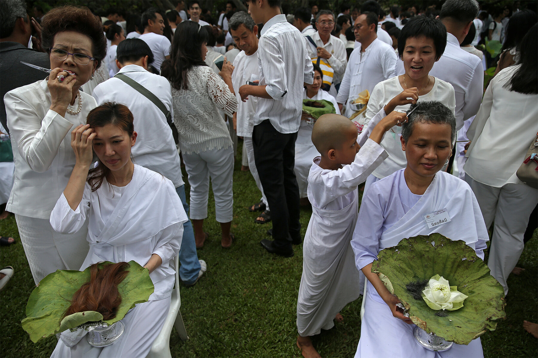<p>Тайские подданные бреют волосы членами своих семей во время массовой церемонии посвящения монахов, которую проводят в честь первой годовщины смерти короля Таиланда Бхумибола Адуляджа.</p>